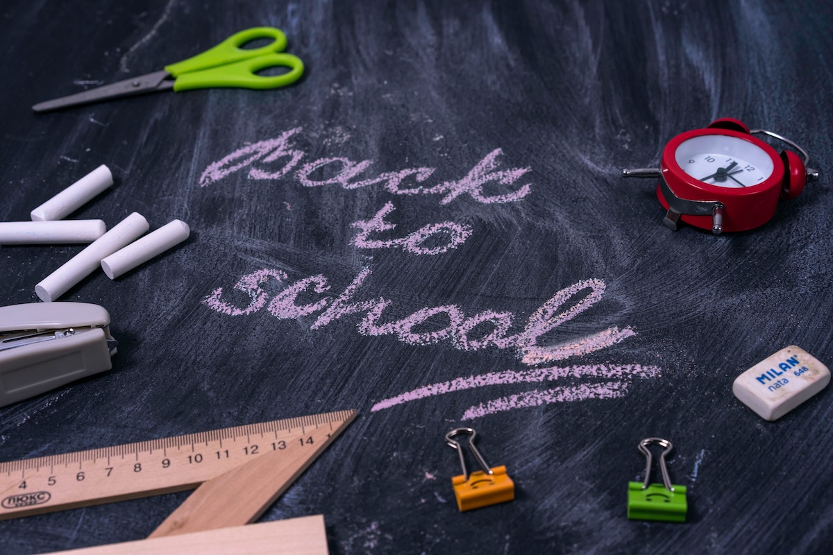 Back to school written on a chalkboard with school supplies around it.