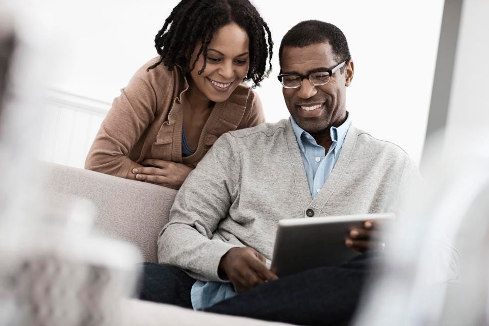 A black couple looks at a tablet together.