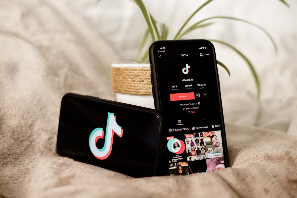 Two phones with TikTok on the screen sitting in front of a plant.