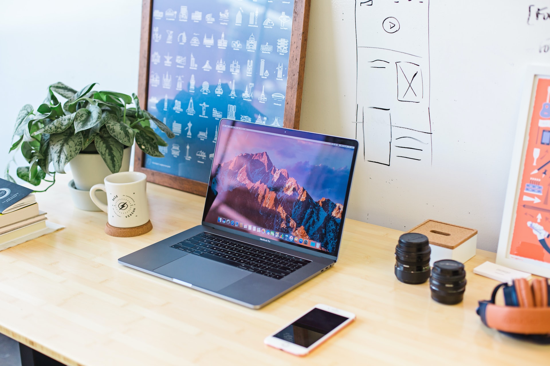 Desk with laptop computer and camera lenses.