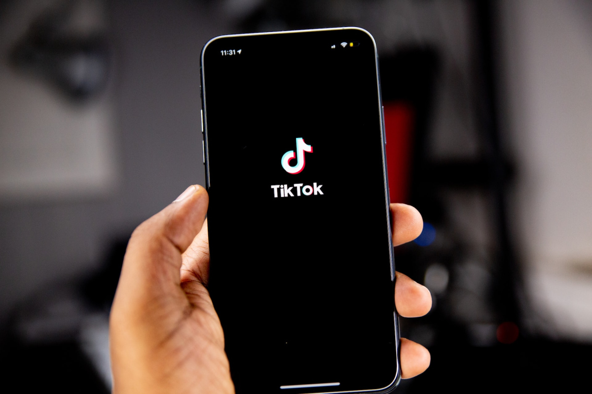 Hand holding up a phone with the TikTok app showing on the screen.
