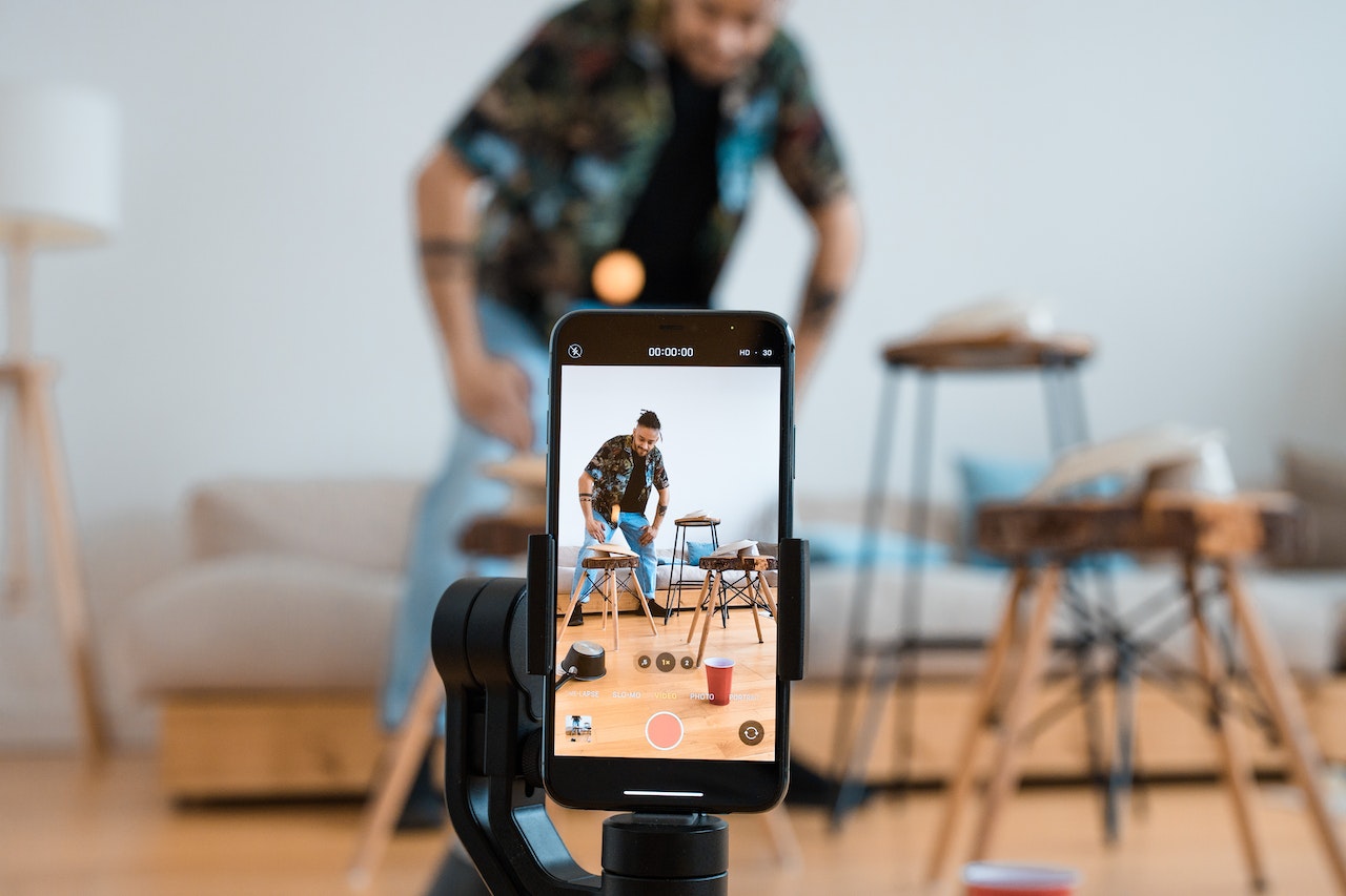 Man capturing a video on a phone in a living room.