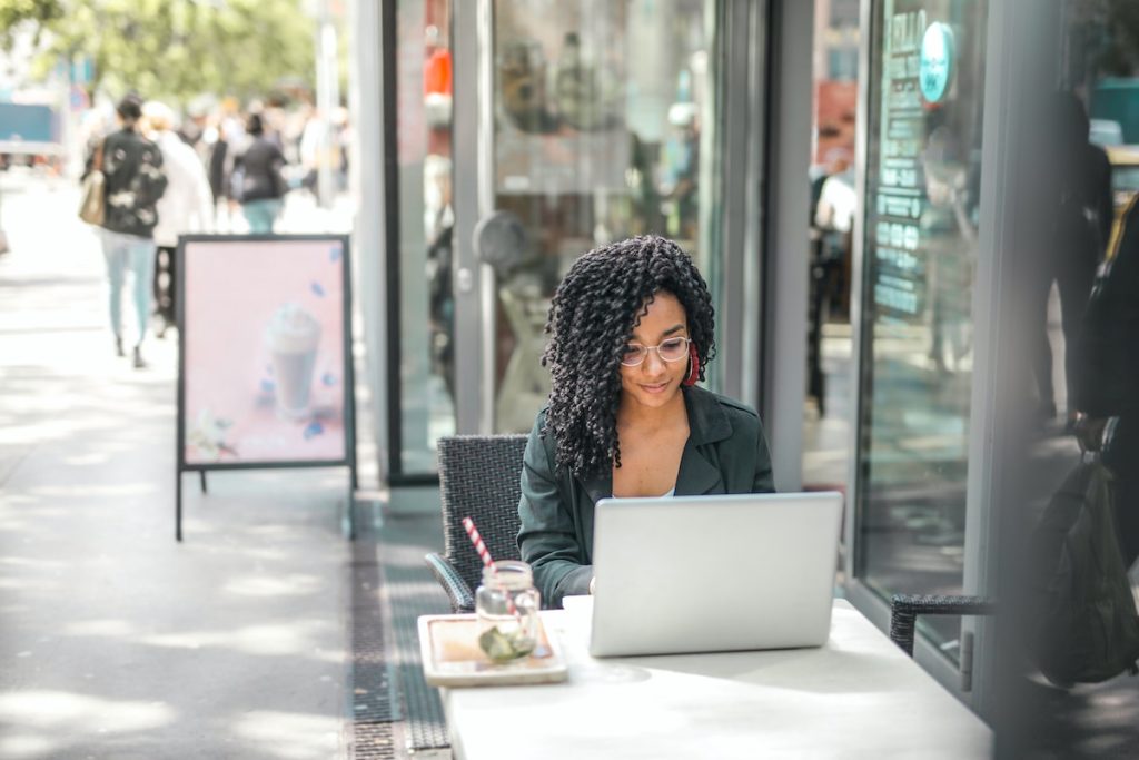 Marketing to millennials picture of a woman sitting at a cafe working on a computer.
