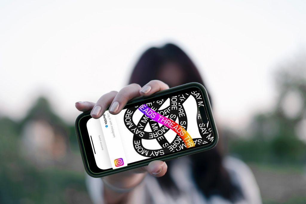 Person holding a phone up with the Instagram Threads logo showing on the screen.