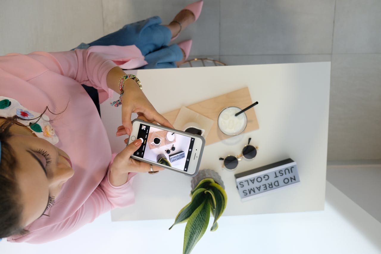 Woman holding a phone and taking a UGC picture of products from above. 