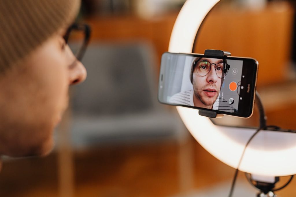 Camera surrounded by a ring light with an image of a man who is creating video content.
